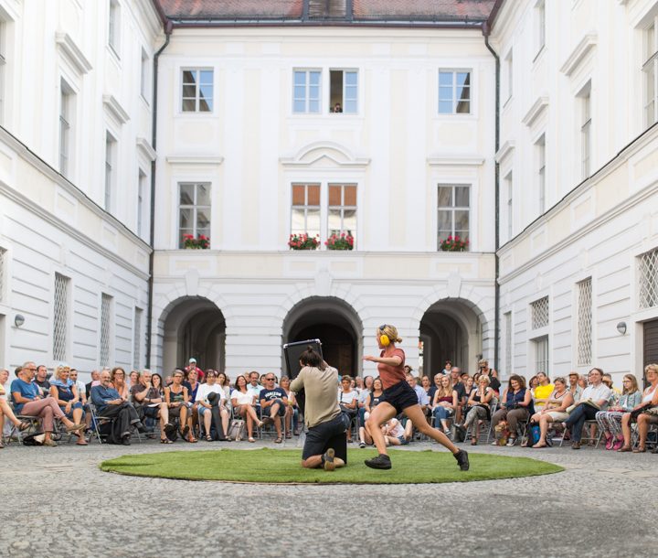 Innenhof mit Straßentheater in der Mitte, Publikum sitzt rundherum