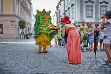 Frau in Rot spricht mit einem Mann, der als Drachen verkleidet ist