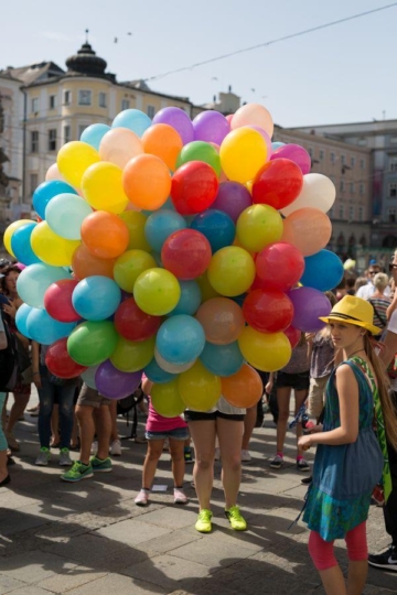 Frau mit vielen bunten Luftballons steht am Hauptplatz